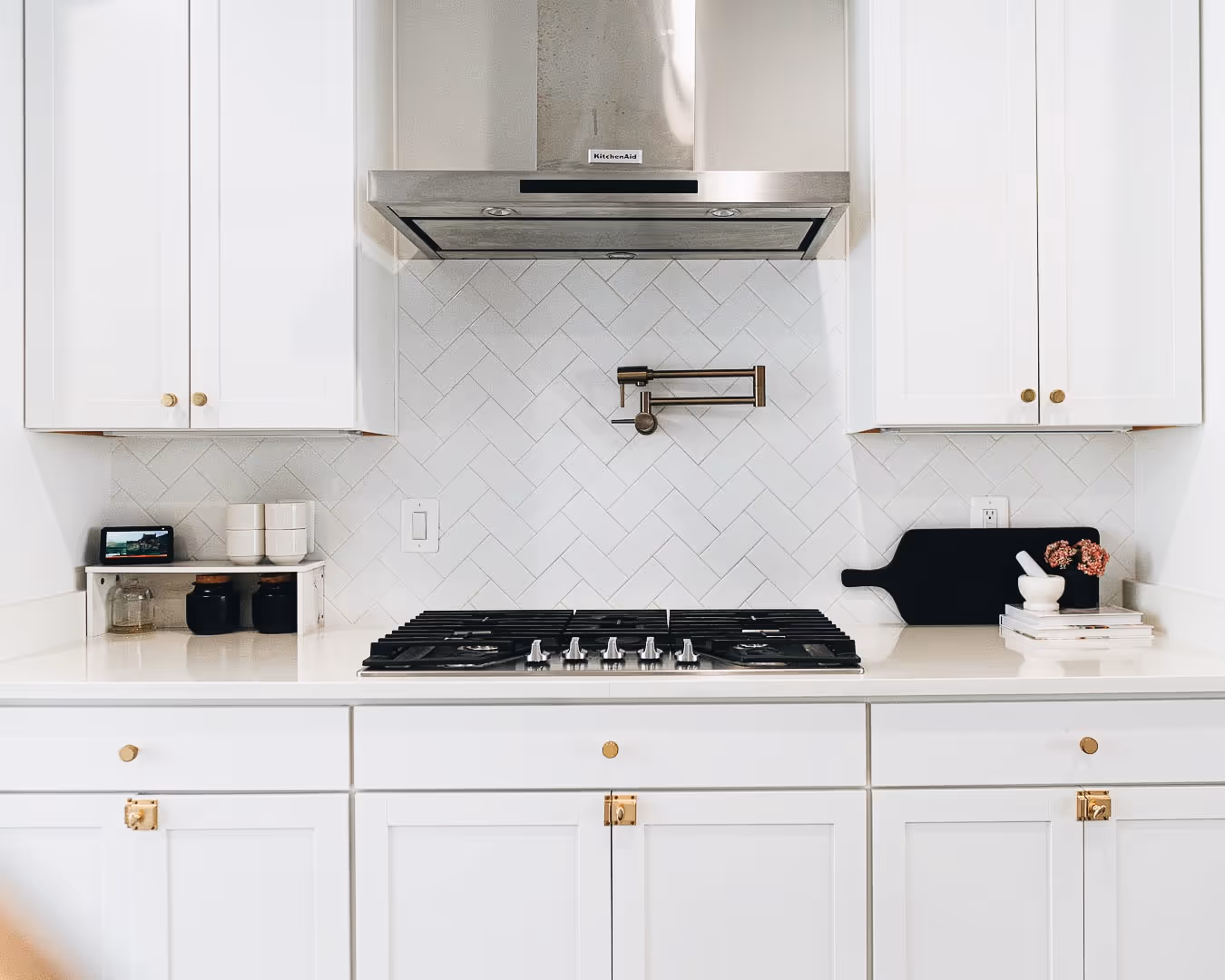 A white kitchen with a stove top oven and a vent hood.