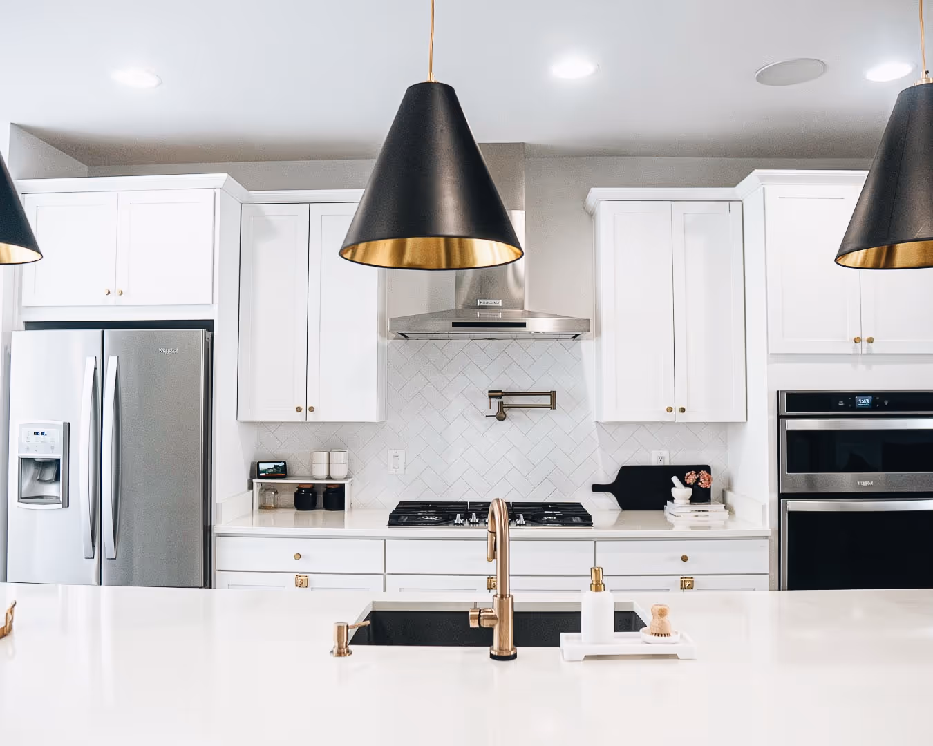 A kitchen with a black and gold light hanging over the stove.