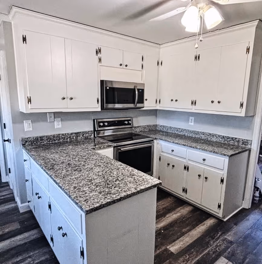 A kitchen with white cabinets and a black stove.