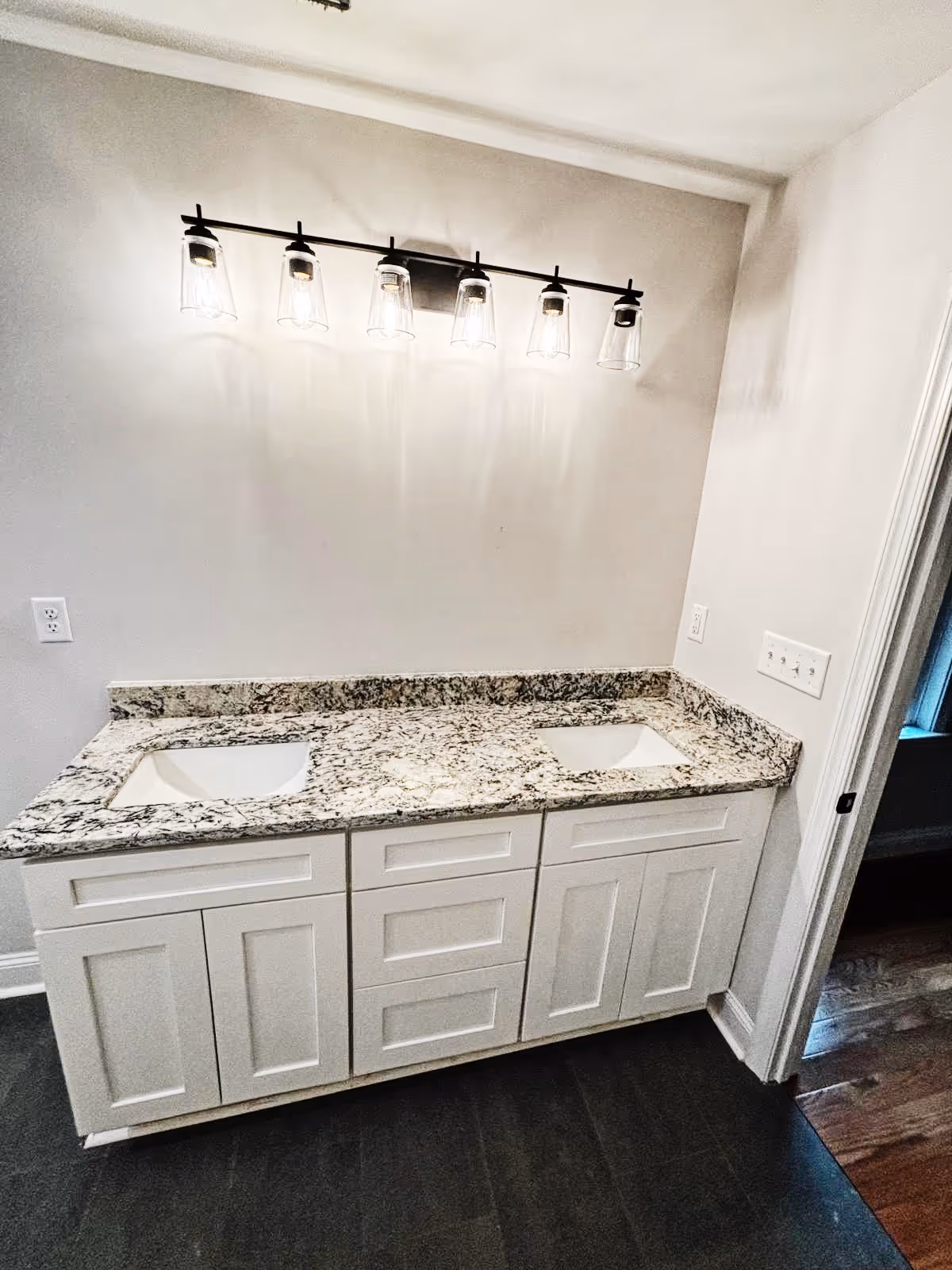 A bathroom with a double sink and a light hanging above it.