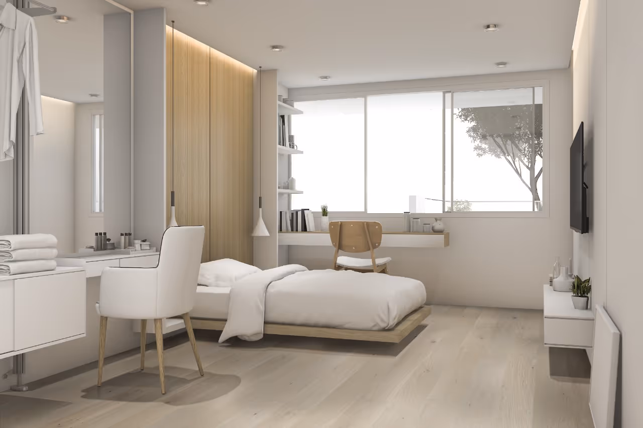 A bedroom with a white bed and a wooden dresser.