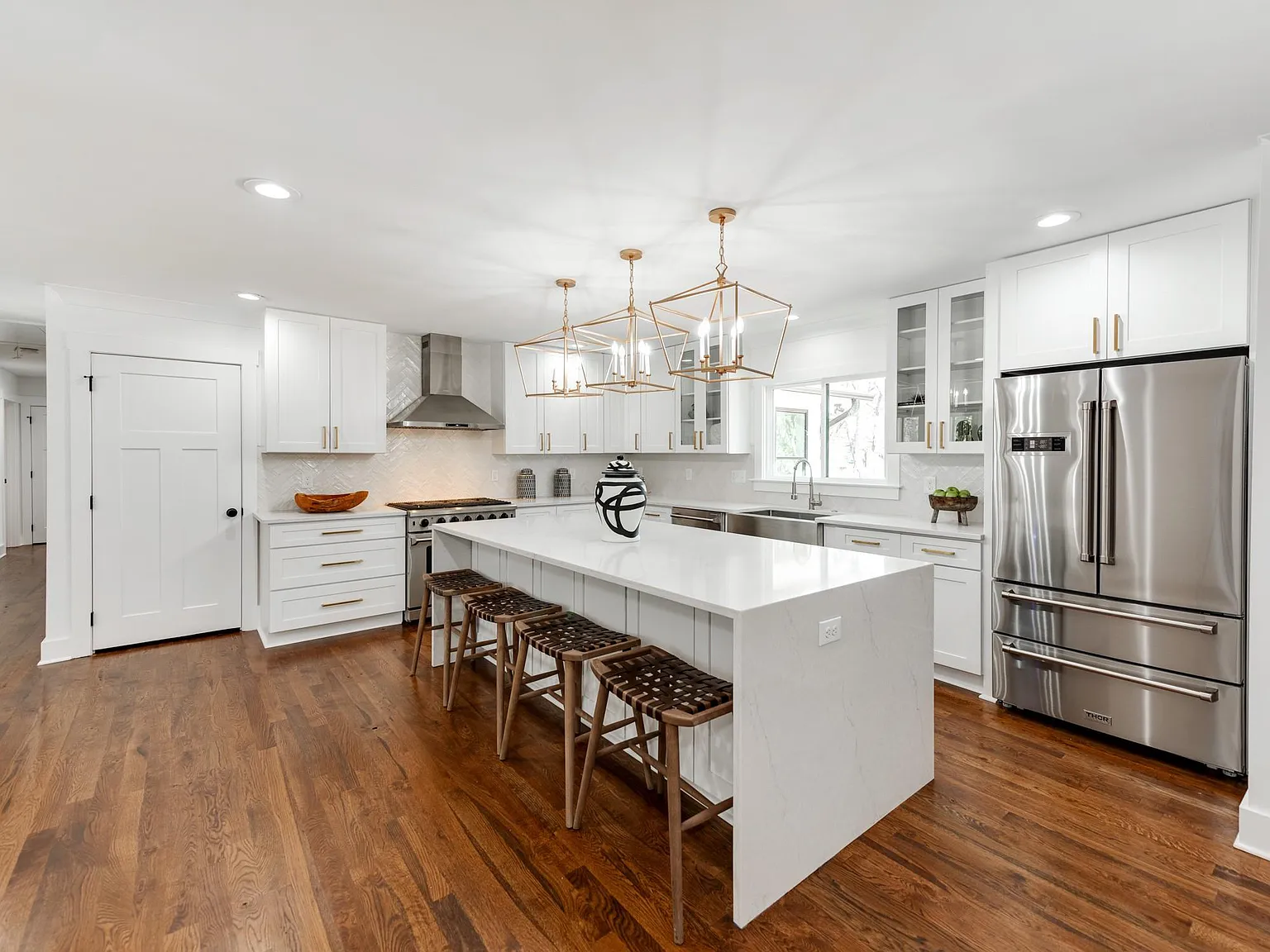 A kitchen with a white island and stainless steel appliances.
