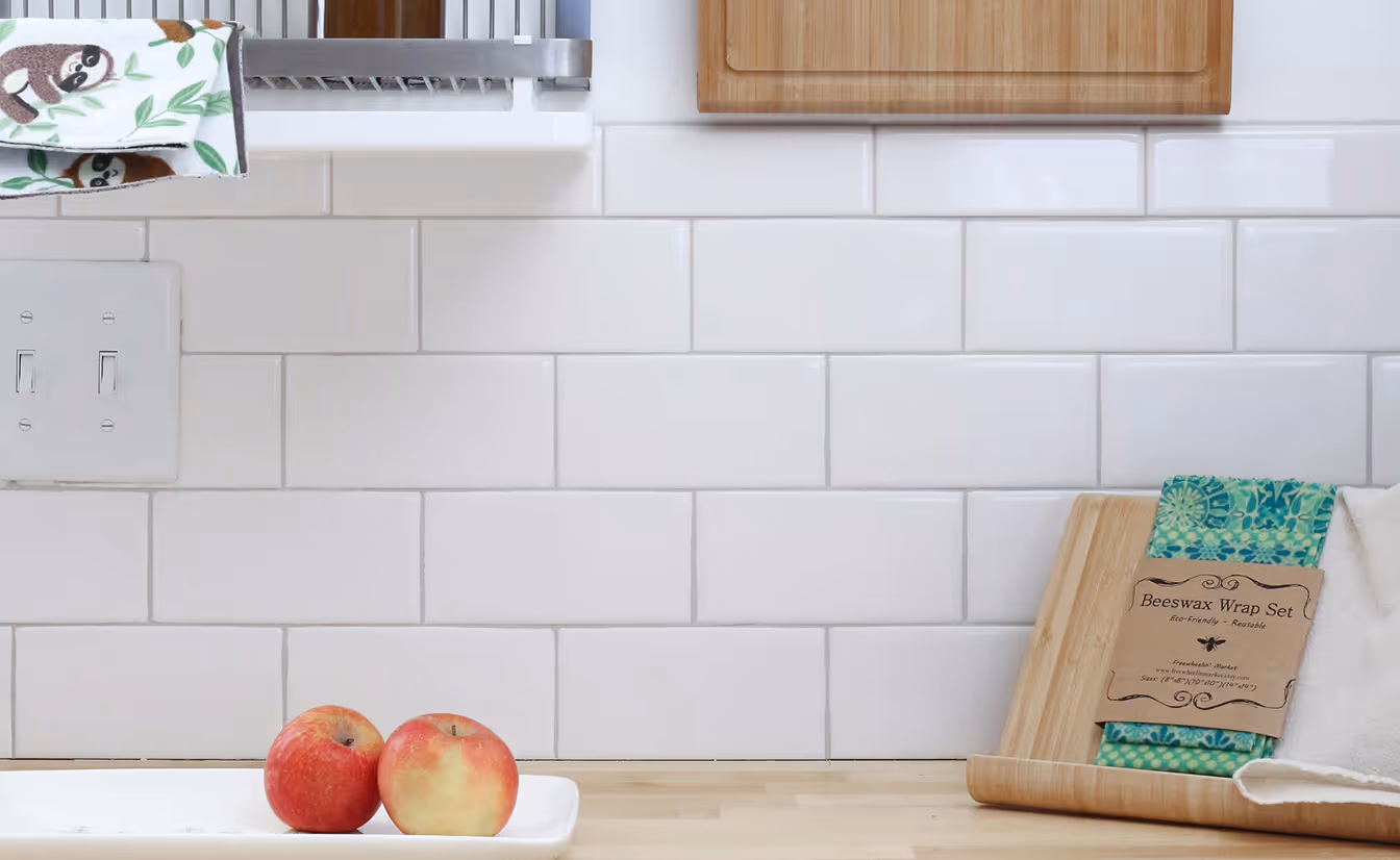 Two apples on a white subway tiled wall.