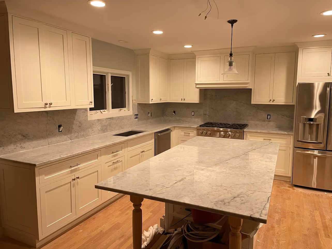 A kitchen with a marble counter top and white cabinets.