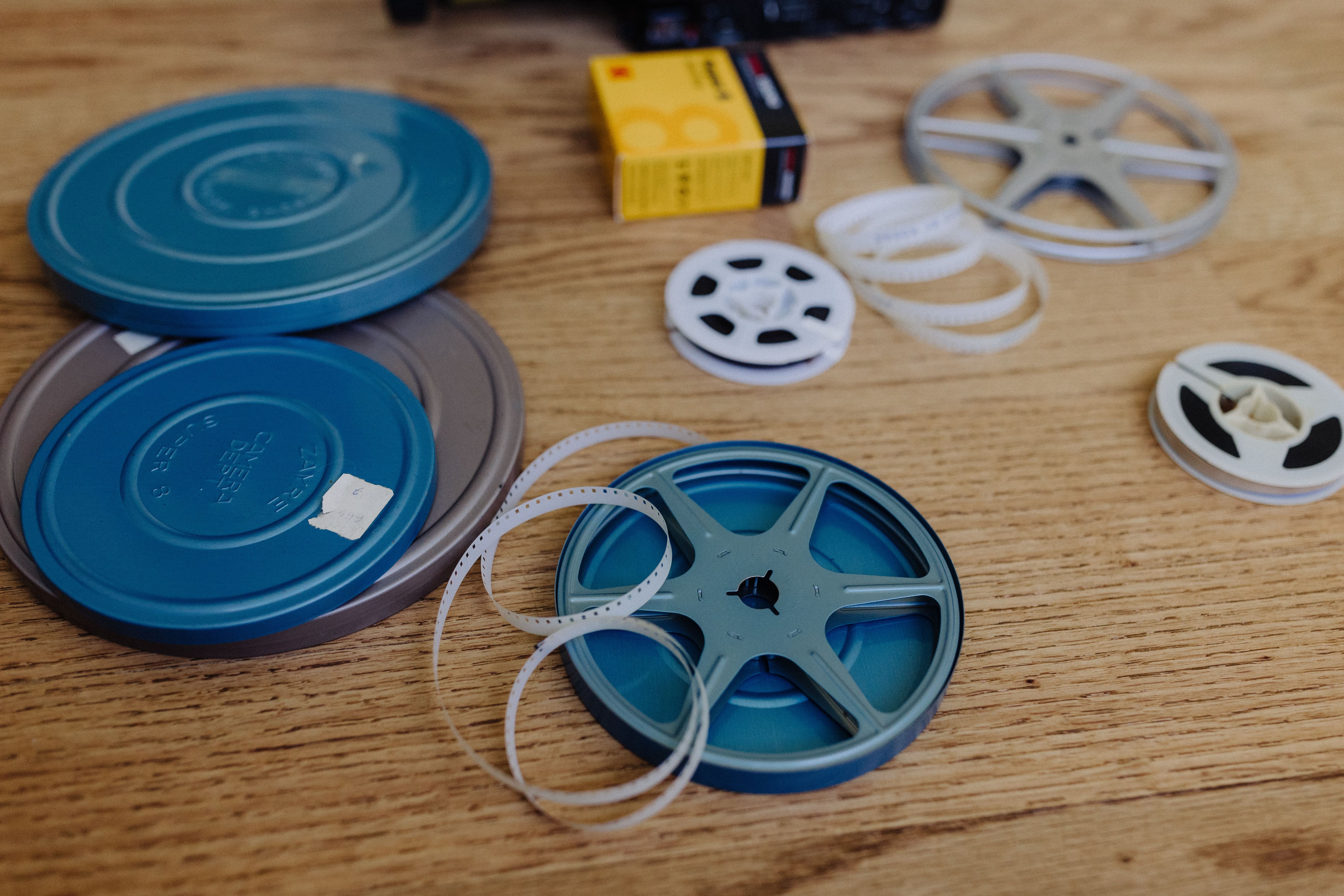 Super 8 film cartridges and film reels scattered in greyscale image