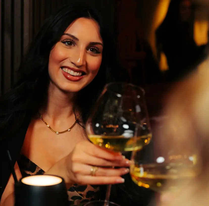 Elegante Frau stößt feiert mit ihrem Partner einen romantischen Abend im MOGGI