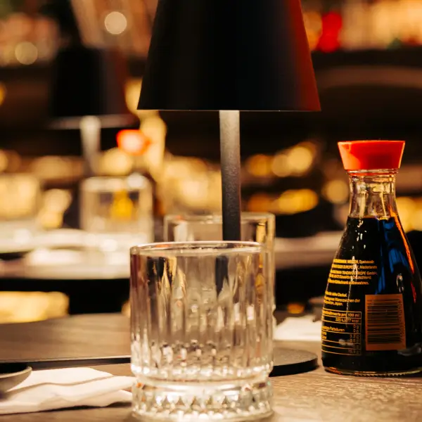 Tisch mit Glas und Sojasauce zeigt das gemütliche Restaurant und Club Ambiente im MOGGI Nürnberg