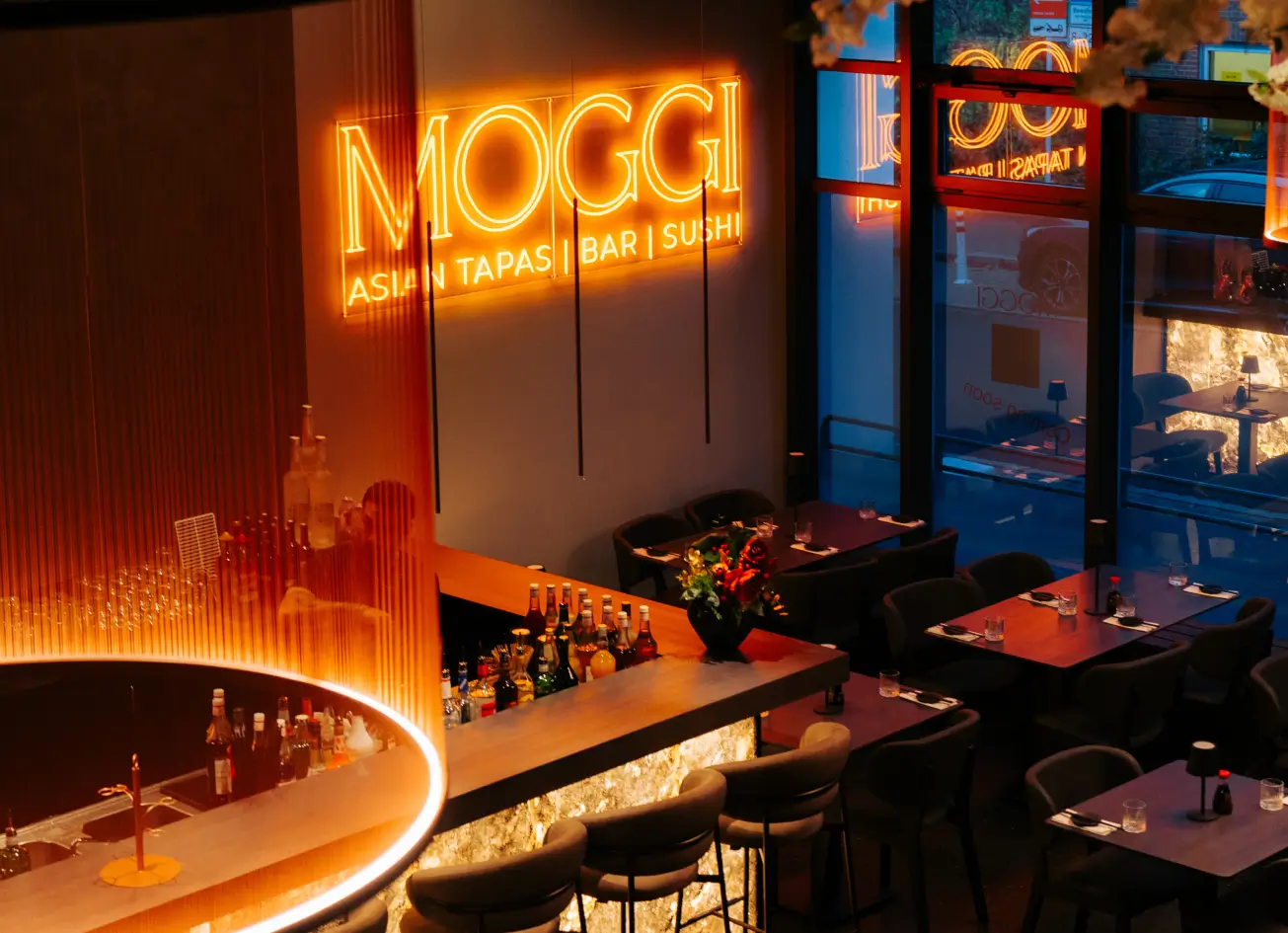 Blick auf beleuchteten MOGGI Schriftzug und Bar