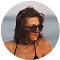 A woman wearing dark sunglasses and a tank top, smiling outdoors.