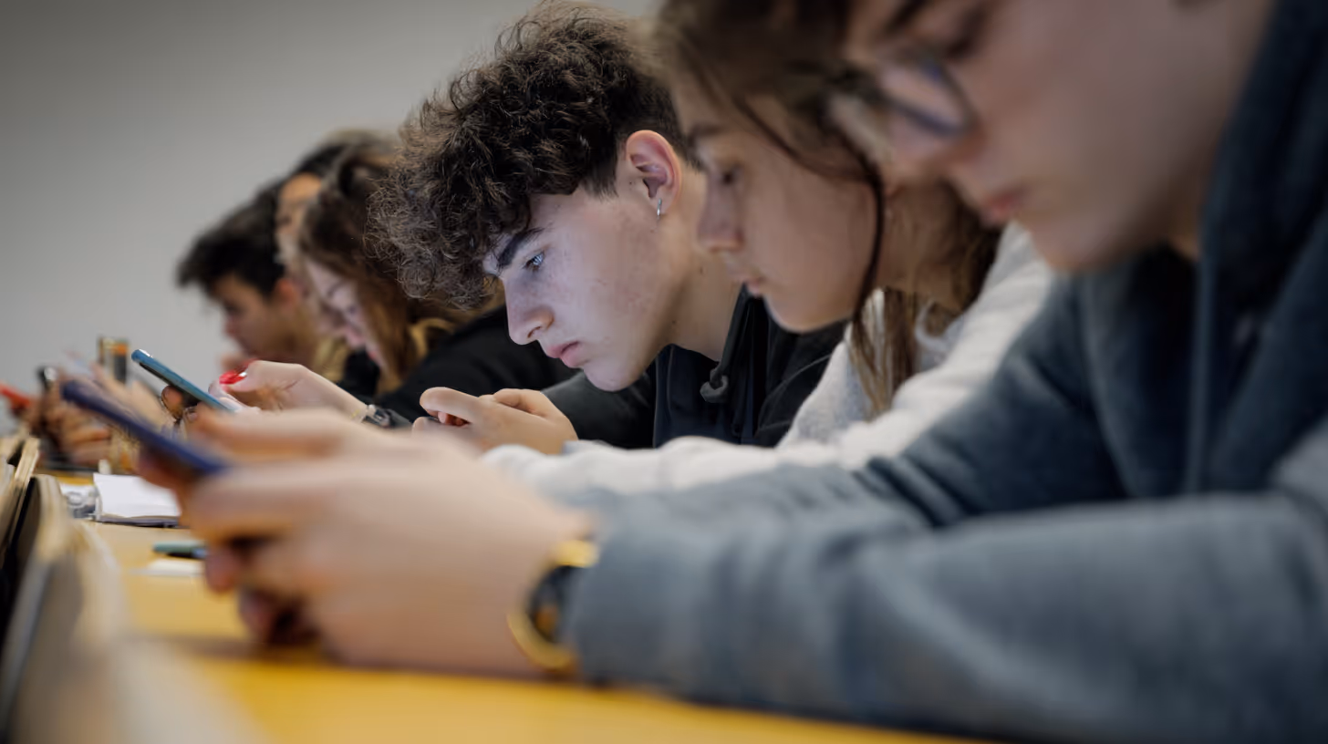 Lycéens absorbés par leurs écrans en salle de classe, représentant le défi éducatif posé par la présence des téléphones portables à l’école.