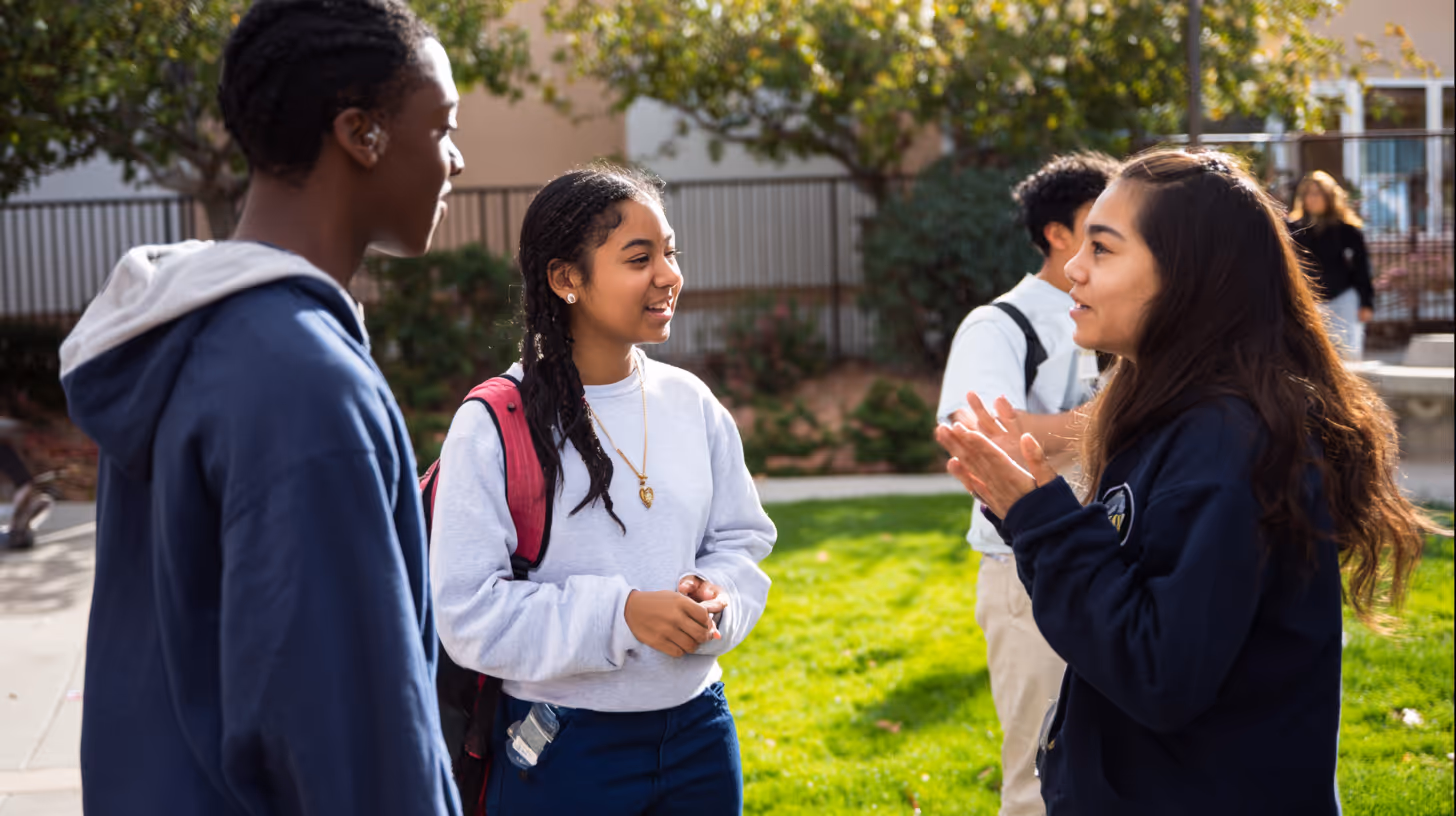 Groupe d’élèves en uniforme scolaire échangeant en plein air sans téléphone, image d’un climat de confiance et d’attention restaurée.