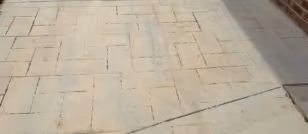 Existing stamped concrete with deep decorative grooves before mechanical grinding