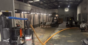 Thick sticky flooring adhesive covering the concrete slab inside a 100 m² private gym before mechanical removal