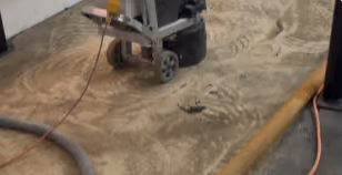Floor grinder mechanically removing stubborn adhesive from the private gym concrete slab