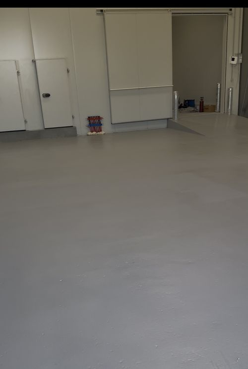Completed grey quartz-textured epoxy floor surrounding insulated doors in the food warehouse