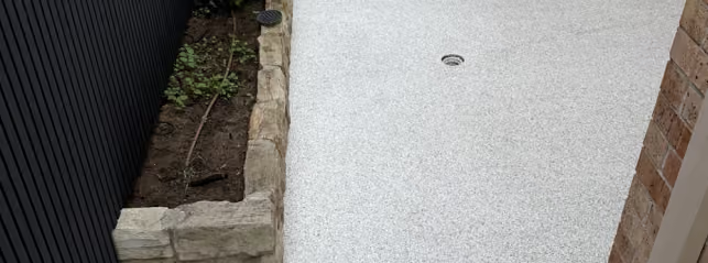 Completed light-grey outdoor epoxy flake flooring beside the garden edge in Baulkham Hills
