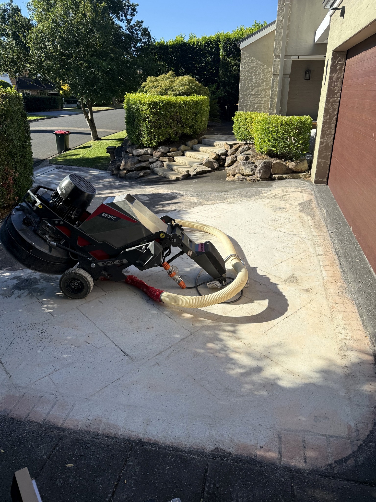 Floor grinder using Redi-Lock diamond tooling to remove a deep stamped pattern from the sloped driveway