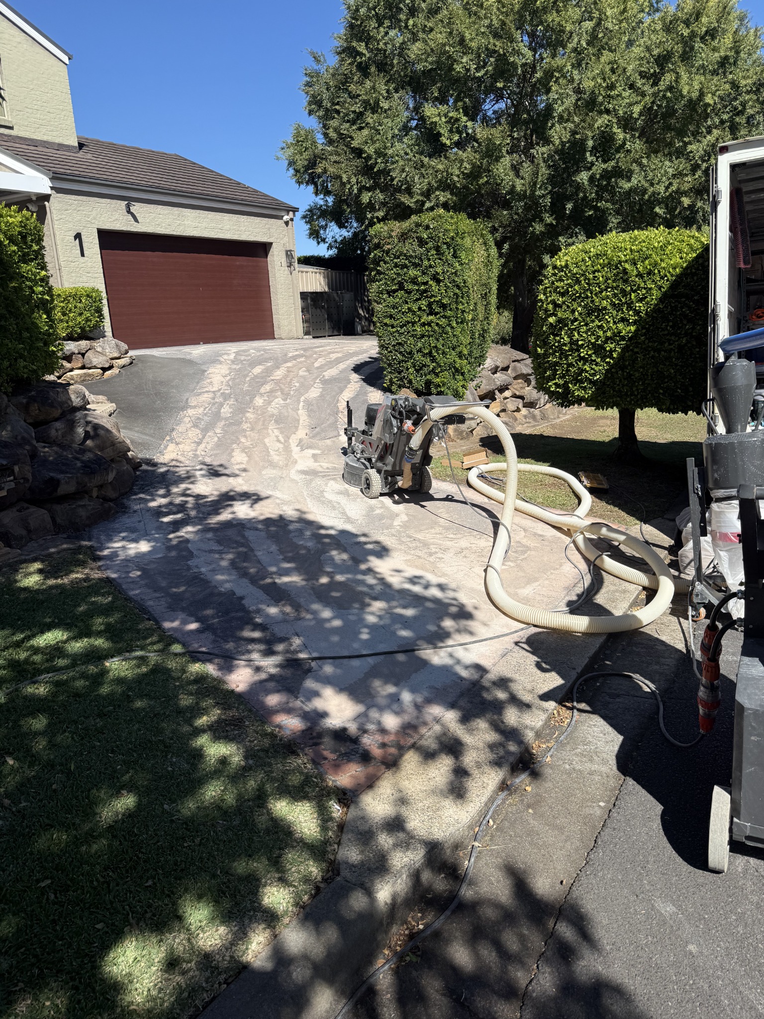 Commercial grinder and extraction equipment completing controlled passes across the sloped driveway
