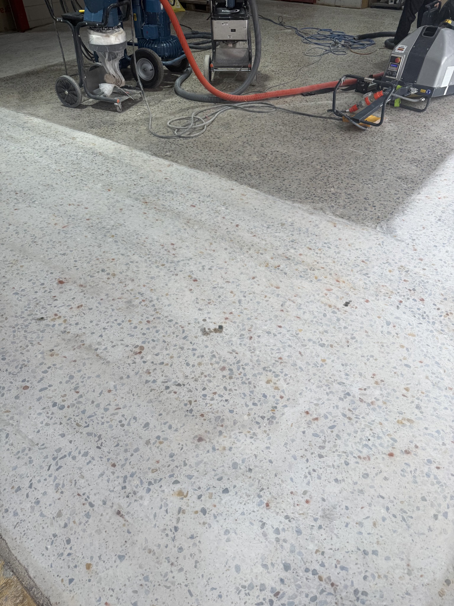 Concrete floor showing lighter and darker sections during the initial mechanical grinding stages
