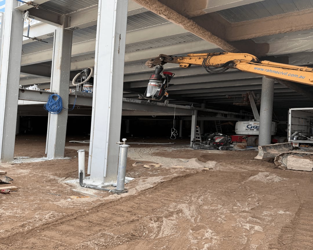 Floor-grinding and dust-extraction equipment staged beneath the elevated slab