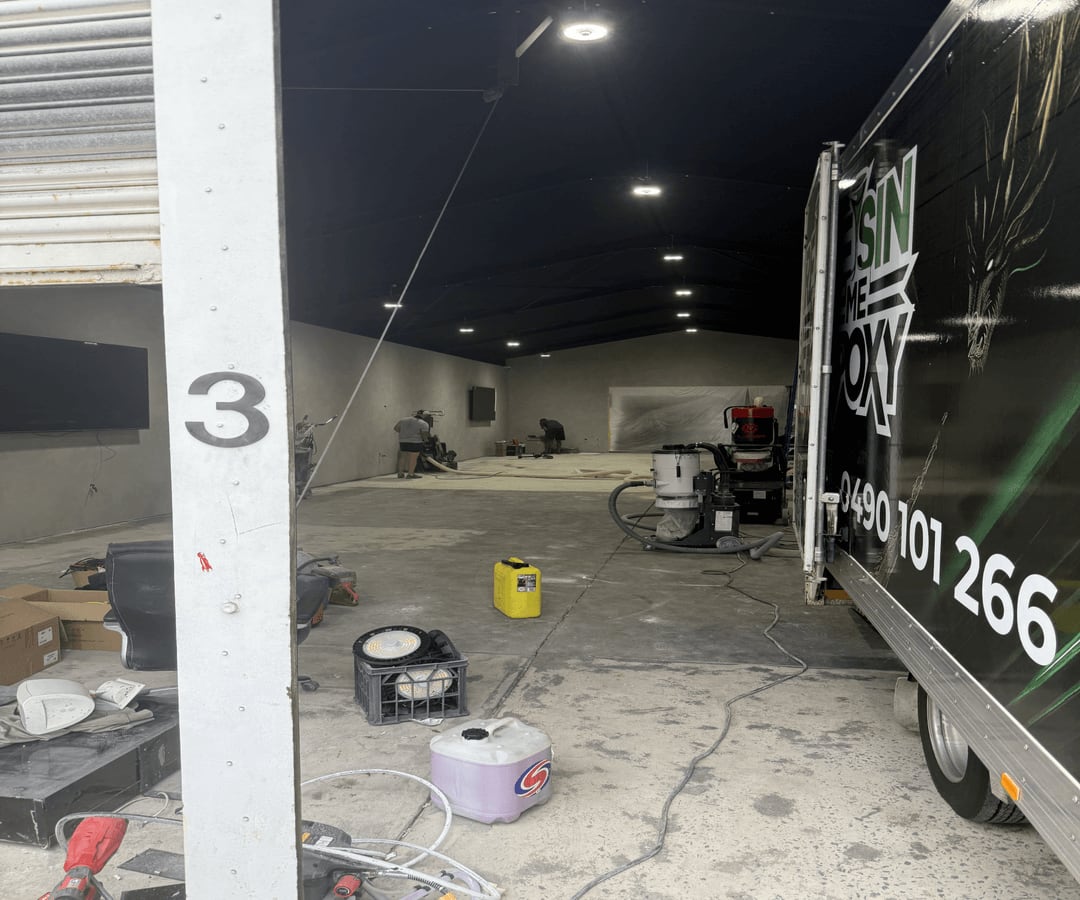 Commercial grinders and dust-extraction equipment preparing a luxury car showroom floor in Parramatta