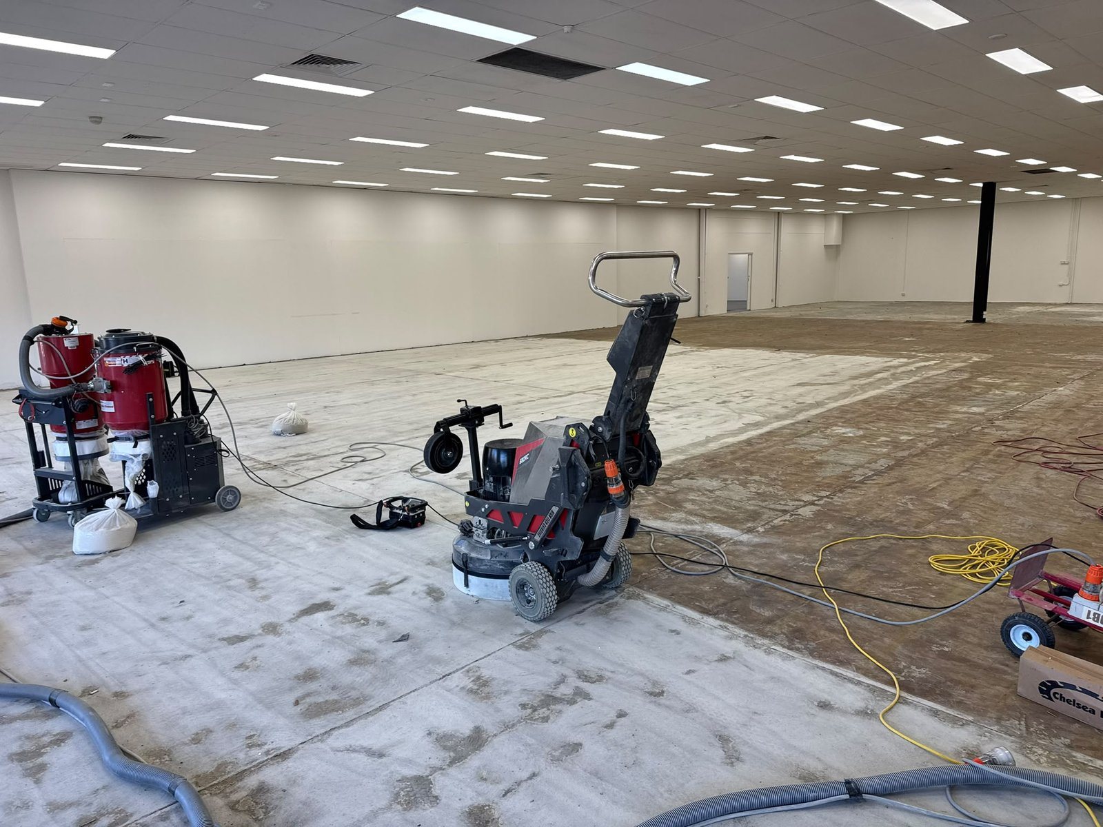 Commercial floor grinder removing adhesive from a 500 m² concrete floor in Sydney