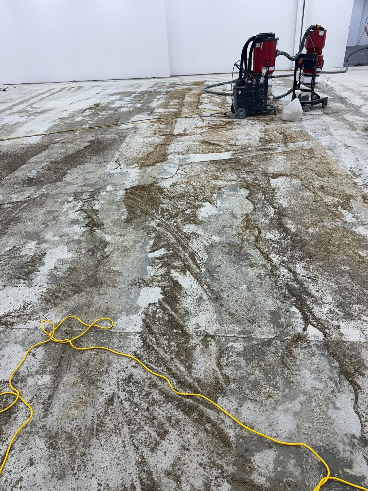 Flooring glue residue exposed during mechanical removal across the 500 m² commercial slab