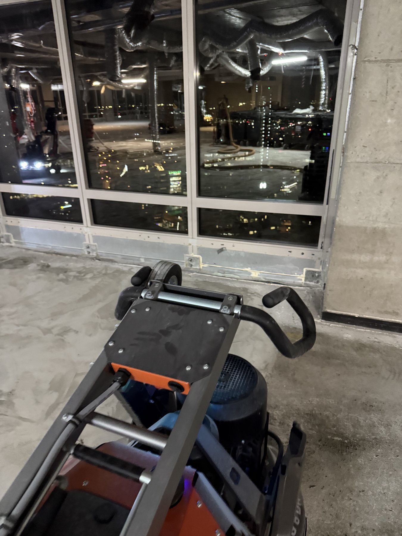 Commercial floor grinder preparing concrete beside perimeter glazing in a Sydney CBD building