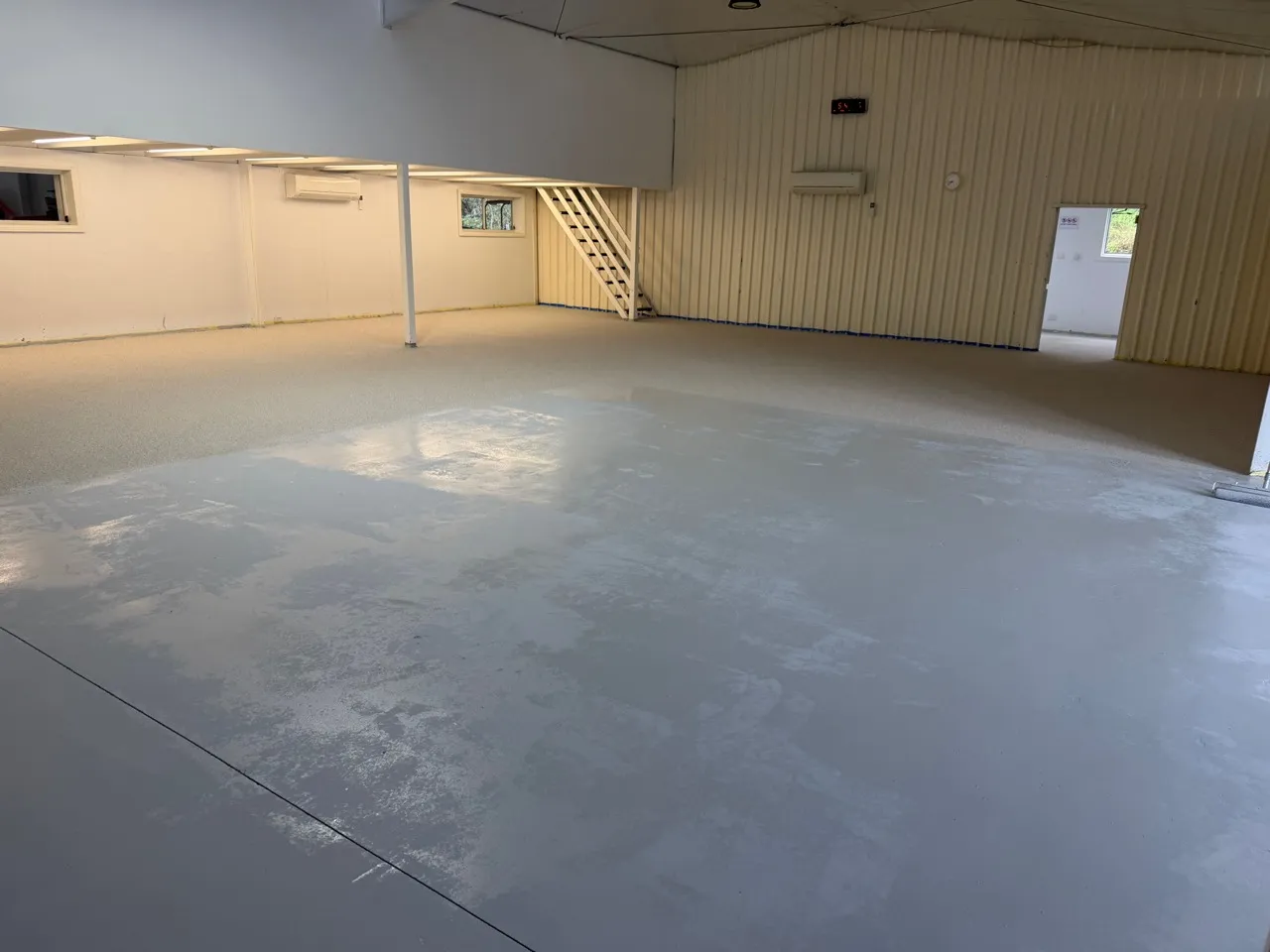 Epoxy flake installation in progress across the hall.