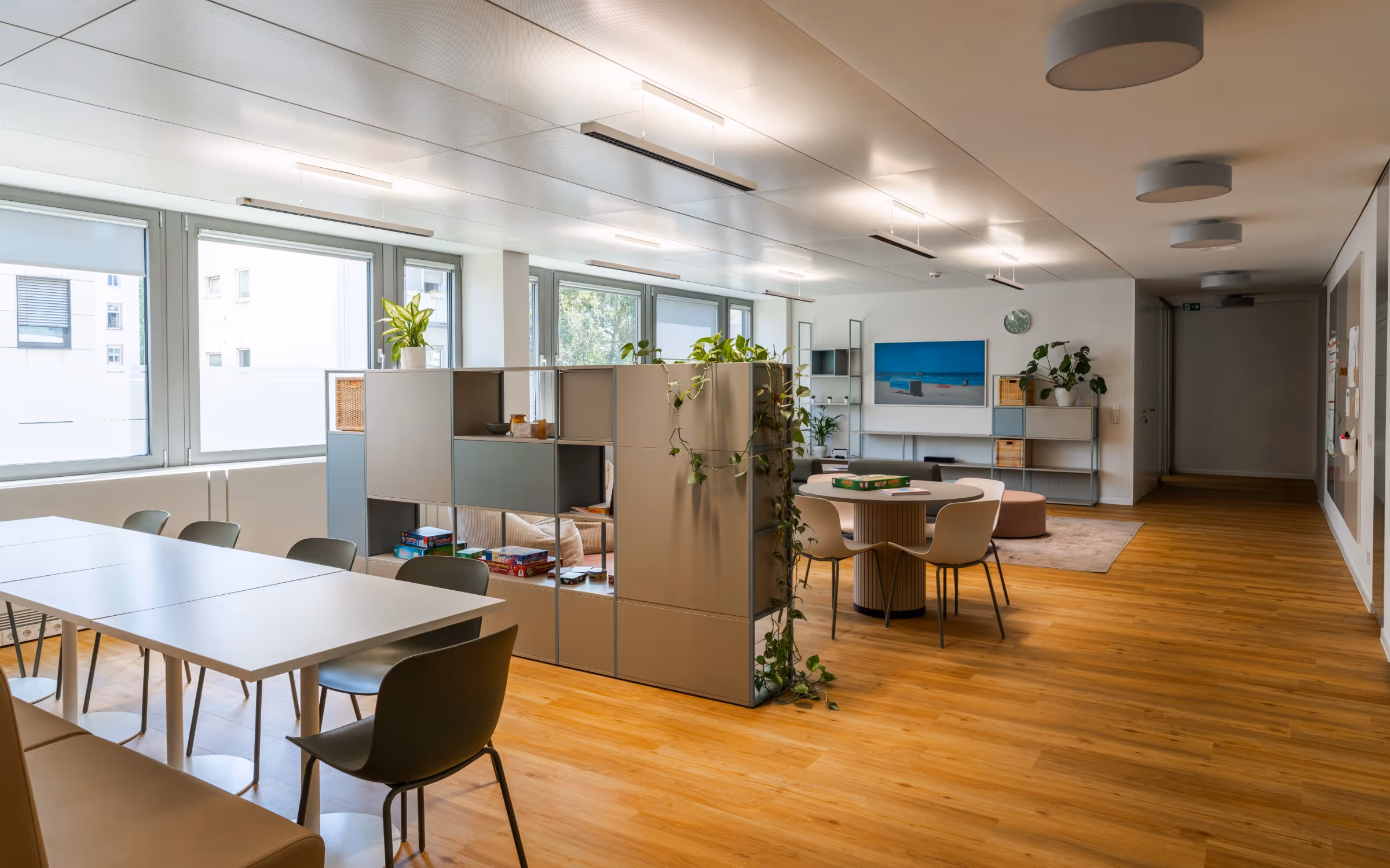 Großer, heller Aufenthaltsraum der Tagesklinik, unterteilt durch ein Raumteiler-Regal.