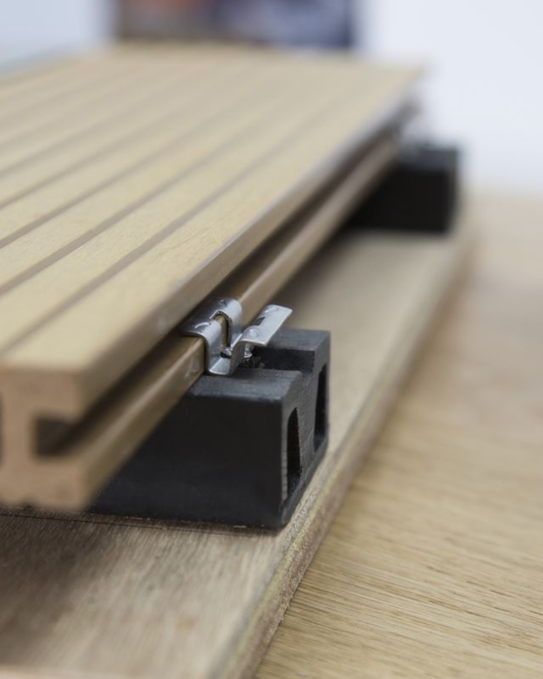 A stainless hidden clip seated between two Tarimatec deck boards on an aluminium joist