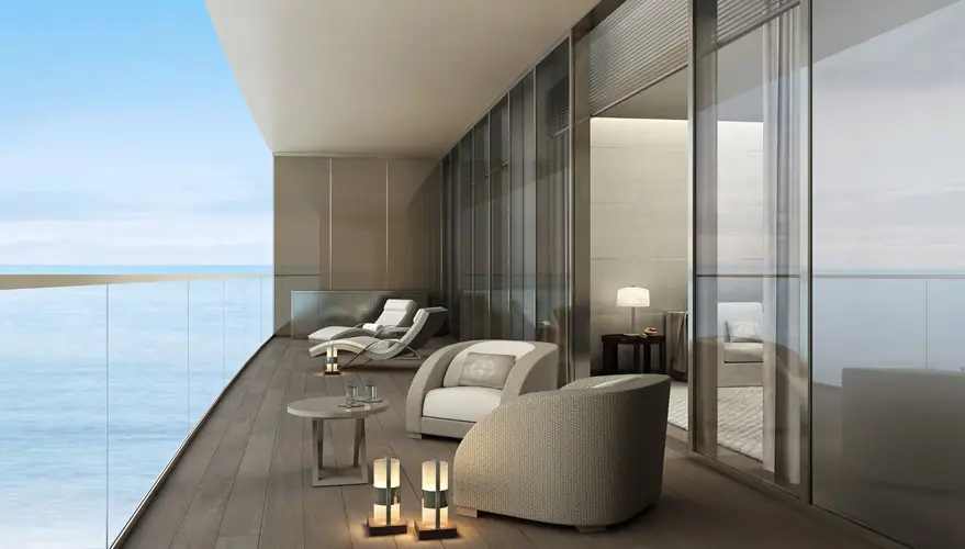 A composite deck balcony with a glass railing overlooking the ocean