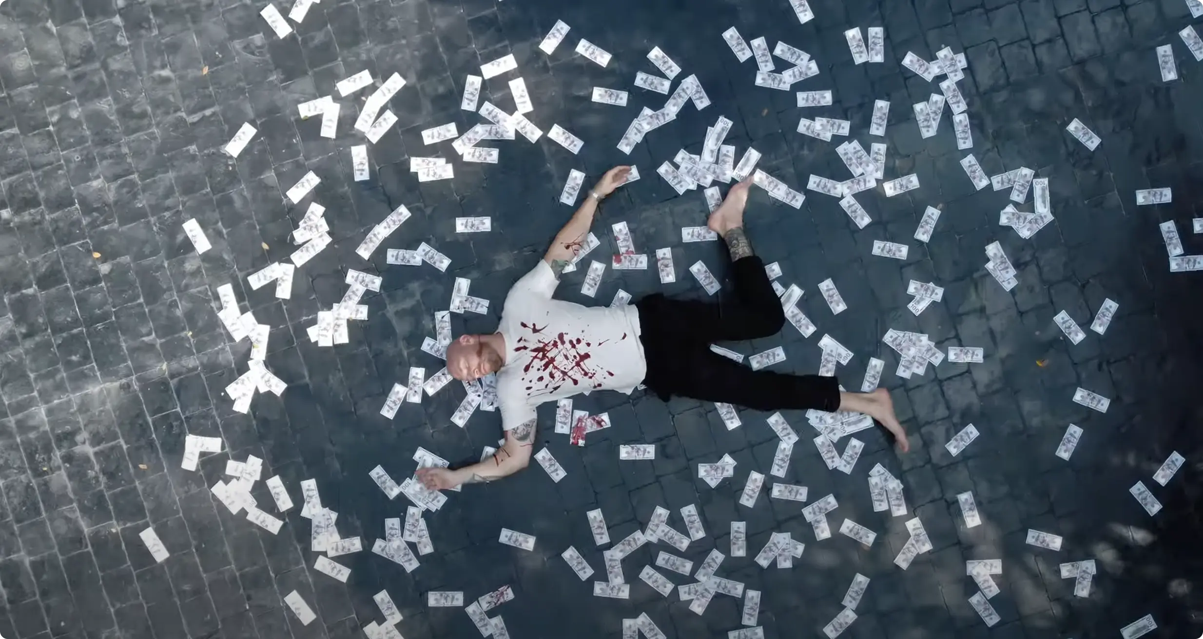 Barami — A man lies on a stone floor covered in scattered banknotes.