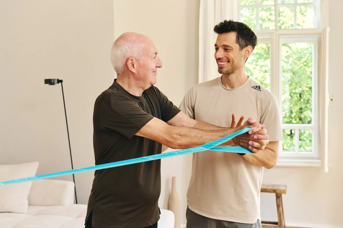 Personal Trainer Lars Traxel demonstriert Fitnessband-Übungen im individuellen Training zu Hause.