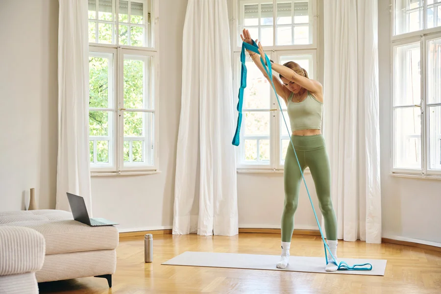 Kundin trainiert mit Fitnessband unter Anleitung von Lars Traxel im Online-Training zu Hause.