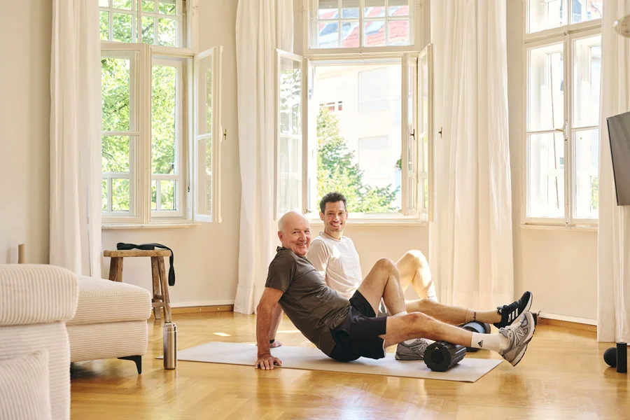Lars Traxel betreut Klienten bei Mobilitätsübungen mit der Blackroll am Boden.