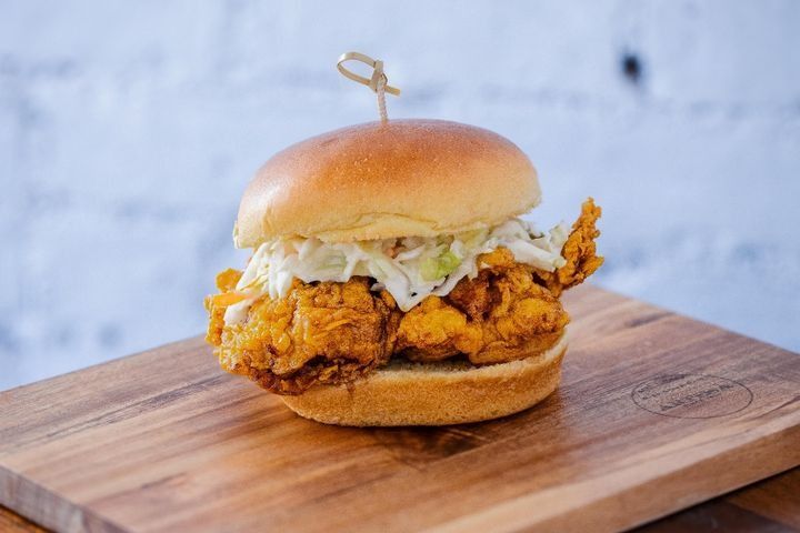 A soy-garlic glazed fried chicken sandwich with coleslaw on a potato bun.
