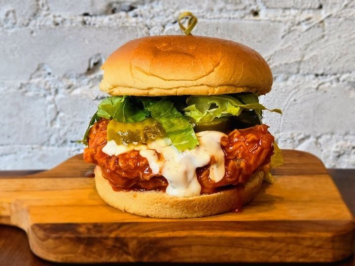 A honey buffalo fried chicken sandwich with coleslaw, pickles, and ranch sauce.