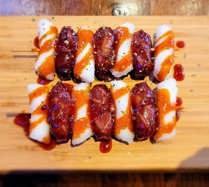 Two skewers of sausage and rice cakes in a sweet and spicy glaze.