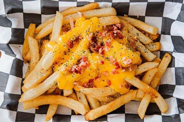 A serving of extra-crispy fries loaded with nacho cheese and bacon bits.