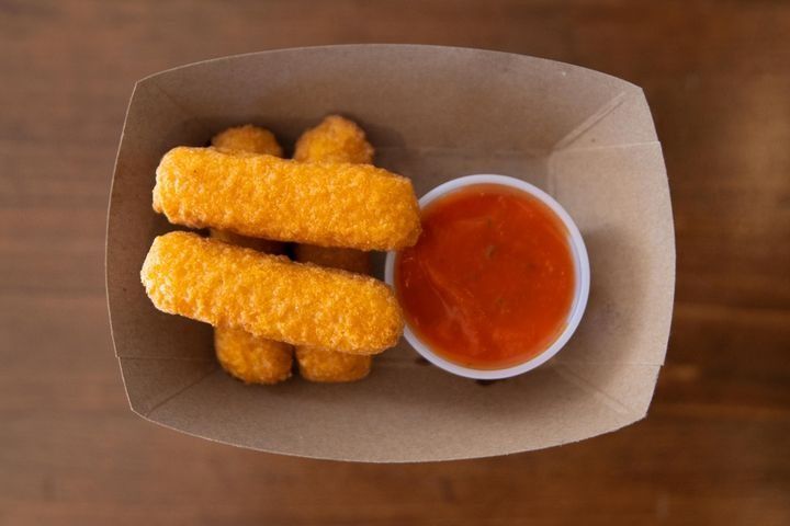 A serving of 4 battered mozzarella sticks with marinara sauce.