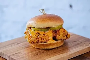 A Cajun seasoned fried chicken sandwich with spicy ranch sauce and pickles on a potato bun.