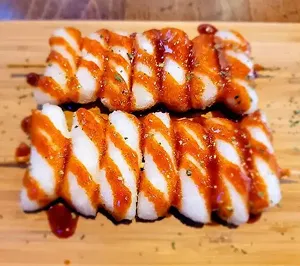 Two skewers of sausage and rice cakes in a sweet and spicy glaze.