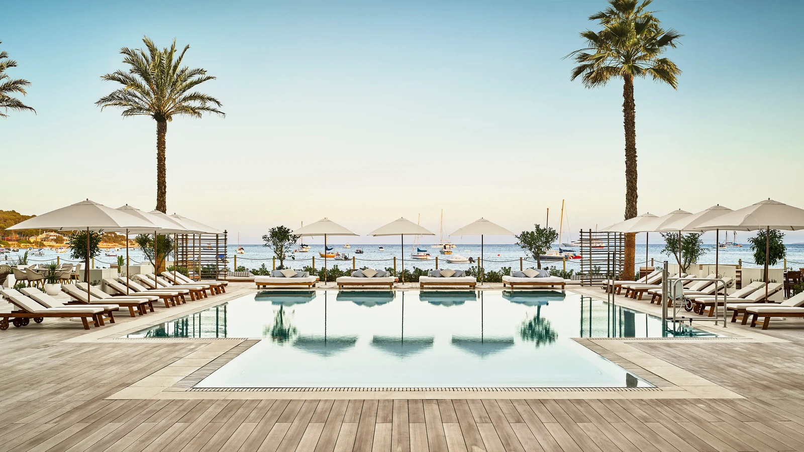 Pool and sun deck at Nobu Hotel Ibiza Bay, Ibiza, with palms and the bay beyond
