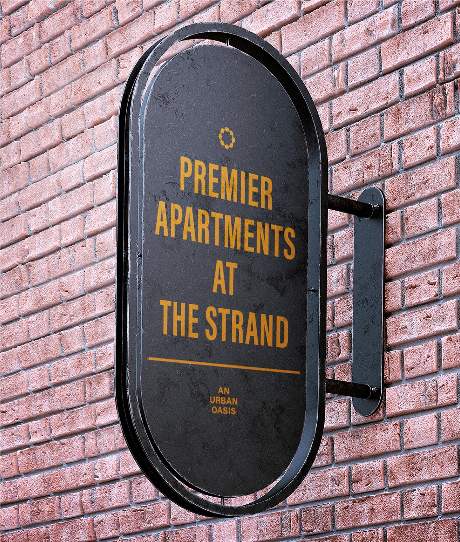 Oval, dark-colored hanging sign for "Premier Apartments at The Strand" with gold lettering and the tagline, "An Urban Oasis," mounted on a textured brick wall.