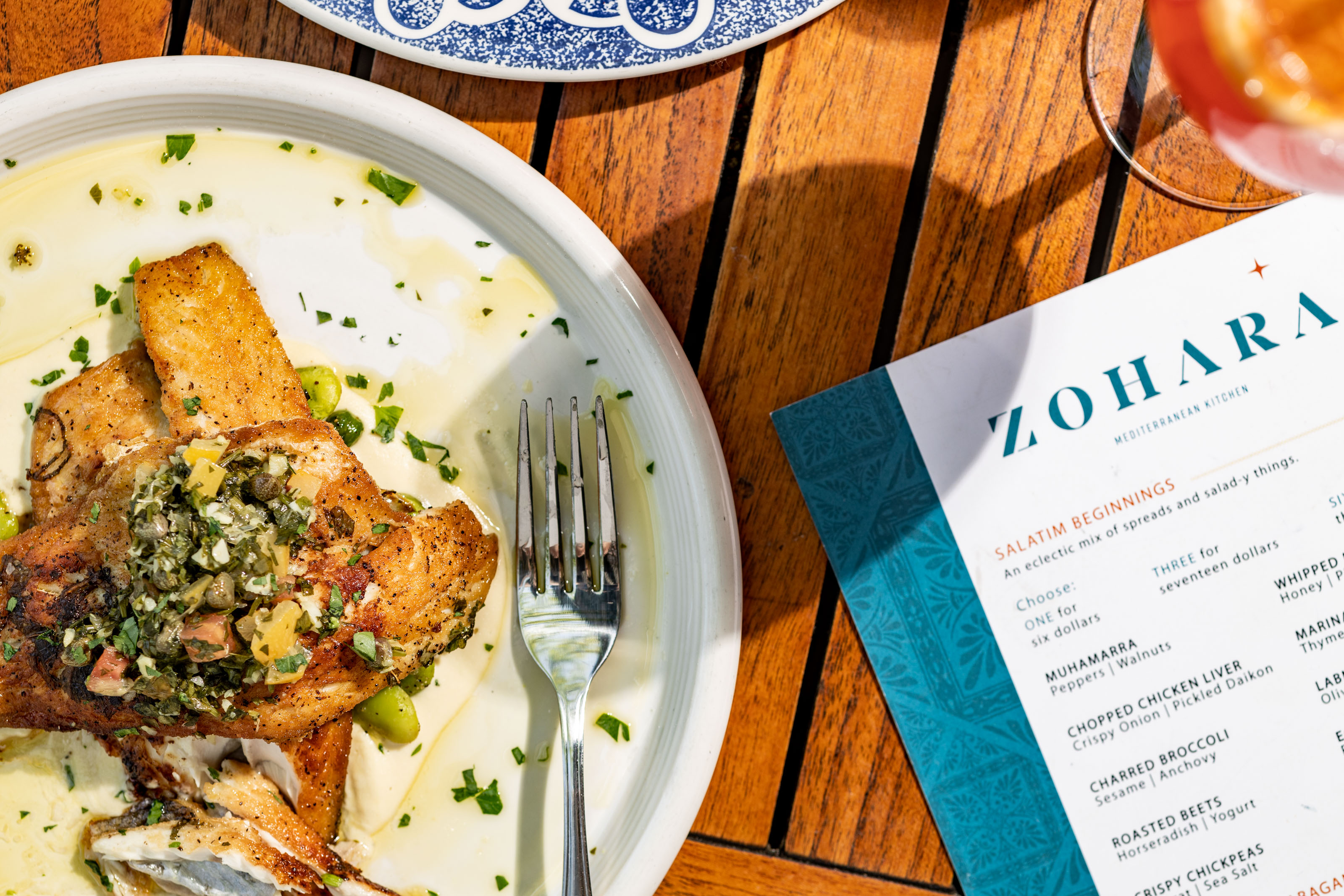 The Zohara menu is prominently displayed next to a plated dish, reinforcing the restaurant's branding.