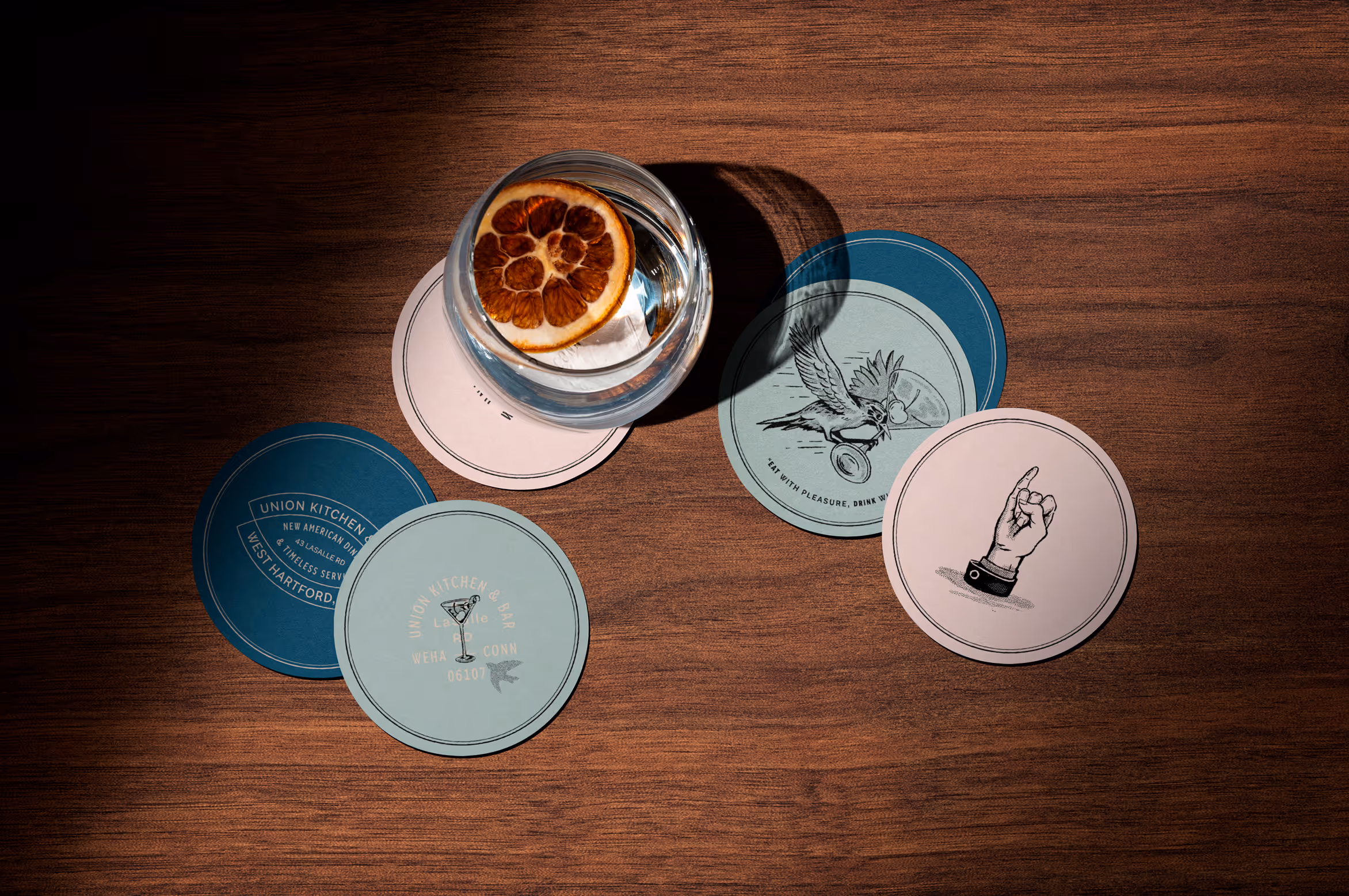 Various coasters, featuring illustrations of fine dining tropes flipped on their head. Shades of blues and pinks add an approachable charm.