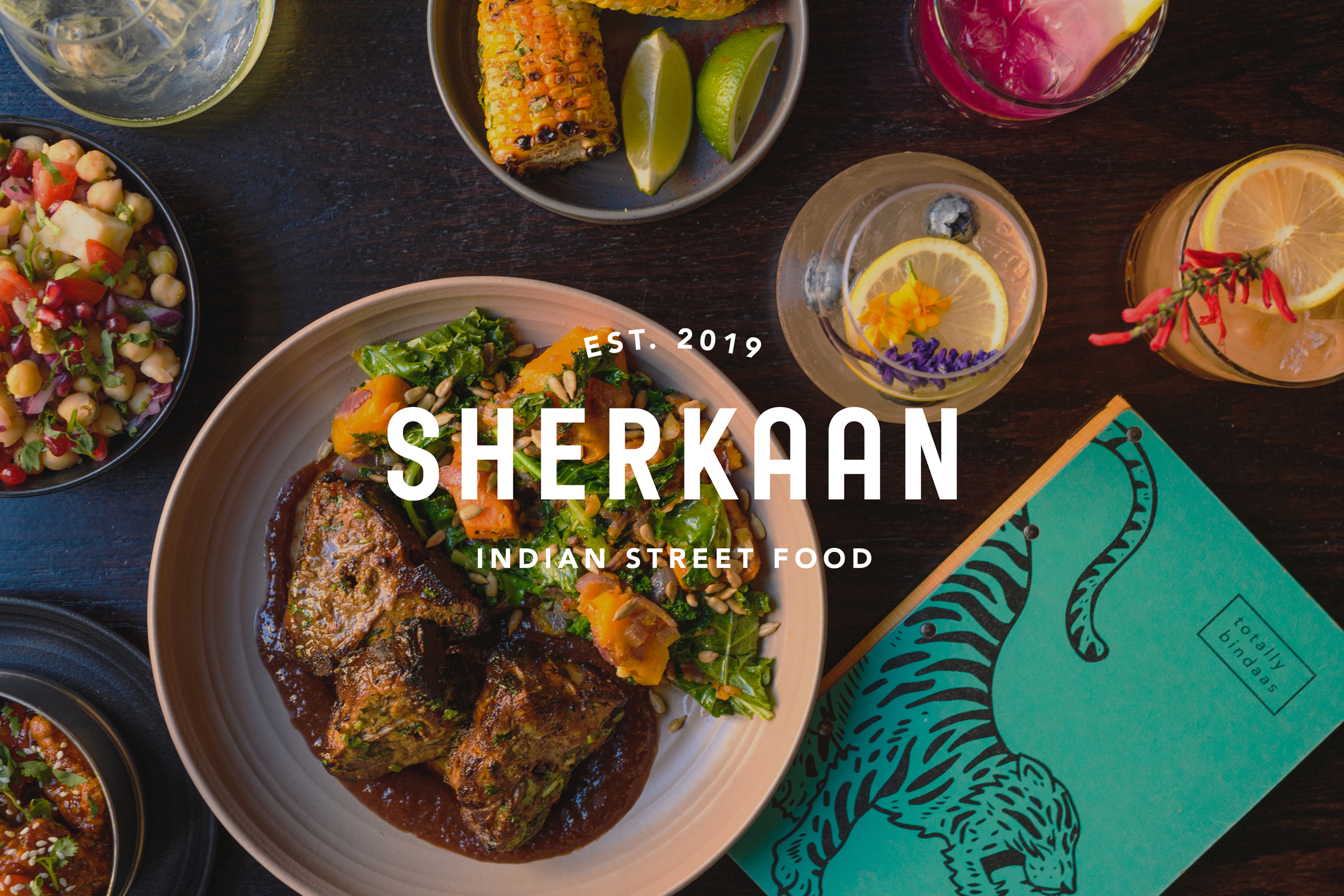 Flat lay design showcasing Sherkaan Indian Street Food's visual identity: a minimalist logo, a vibrant menu cover featuring a stylized tiger, and artfully arranged dishes demonstrating the restaurant's culinary offerings.