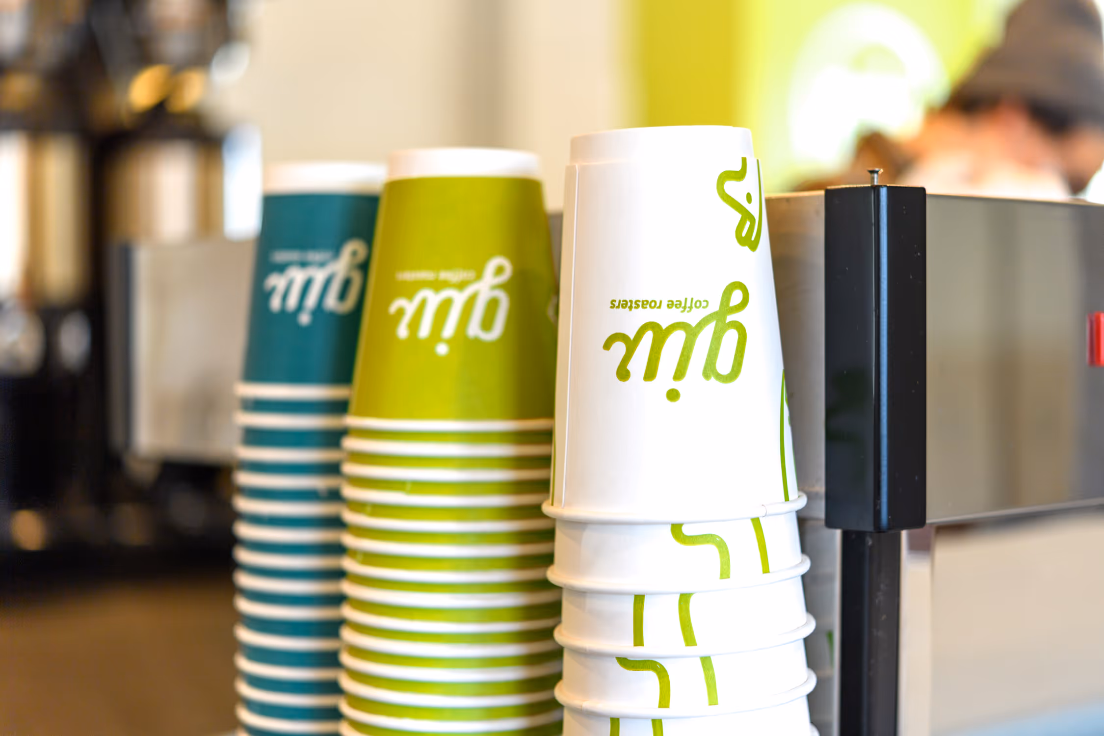 Stacks of Giv Coffee cups in varying color palettes: teal, lime green, and white, featuring a stylized 'Giv' logo.