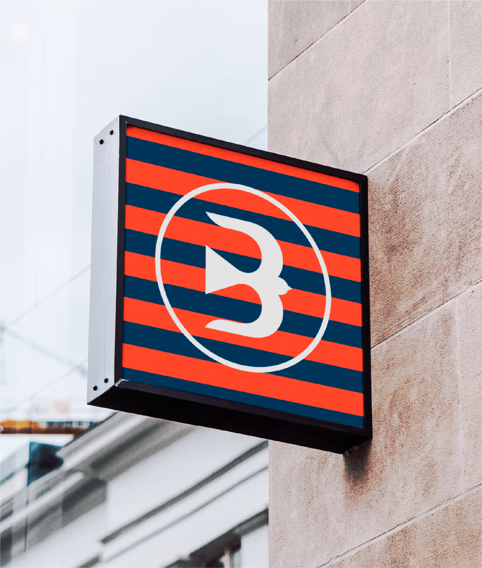 Image of a square building sign featuring a stylized "B" logo within a circle against a striped background, showcasing the brand's visual identity.